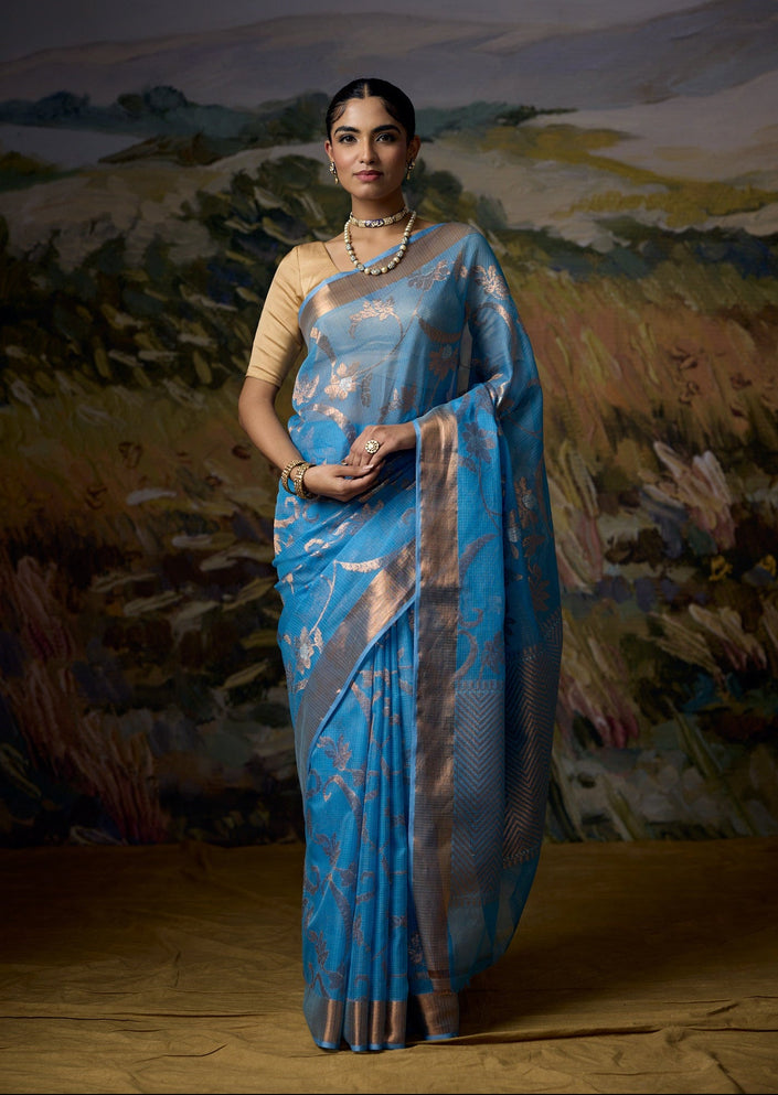 Luxury cobalt blue handwoven Kota saree with gold zari floral jaal, soft green leaf detailing, artistic floral motifs, gold zari chevron pallu, minimal gold border and premium festive designer craftsmanship by Sonchiraiya