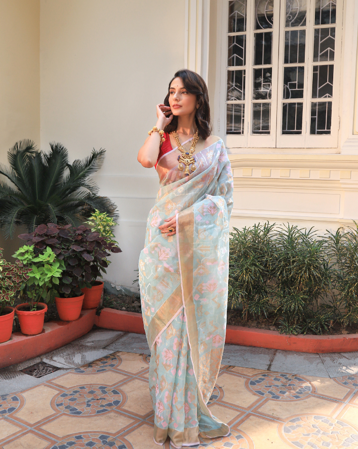 Woman wearing a flowy light blue SónChiraiya zari Kota handloom saree, with silver zari accents, geometric floral motifs, and gold zari borders.