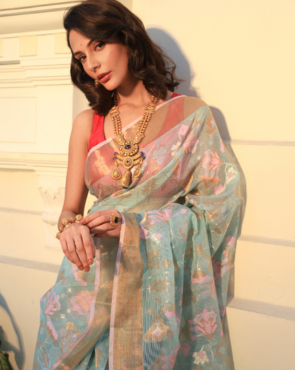 Woman wearing a flowy light blue SónChiraiya zari Kota handloom saree, with silver zari accents, geometric floral motifs, and gold zari borders.