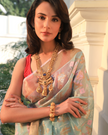 Woman wearing a flowy light blue SónChiraiya zari Kota handloom saree, with silver zari accents, geometric floral motifs, and gold zari borders.