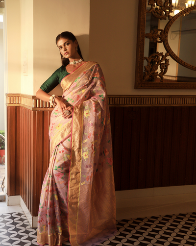 Woman wearing a handcrafted Lavender SónChiraiya zari Kota handloom saree with bright blooming hibiscuses and other bright flowers.