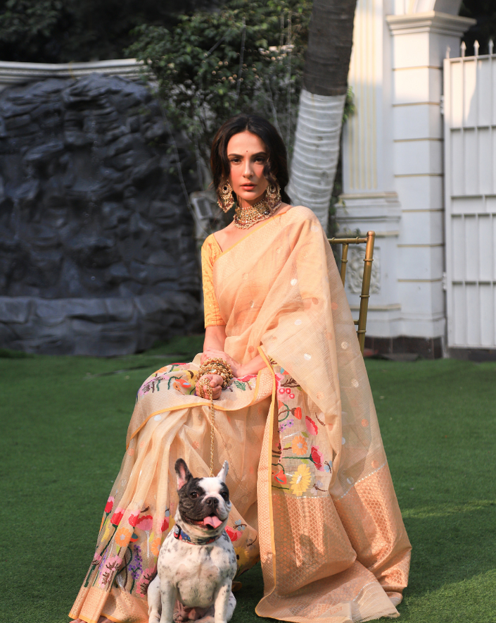 Woman wearing a beige SónChiraiya zari Kota handloom saree, with blooming vibrant flowers, gold and silver zari polka dots and a gold zari border.  
