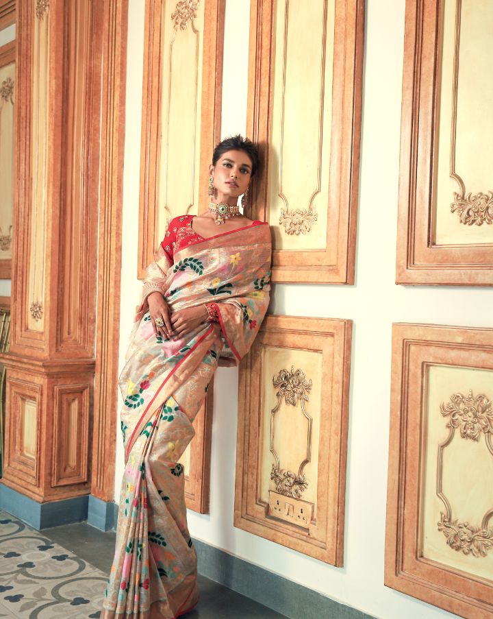 Woman wearing an off-white SónChiraiya zari Kota handloom saree with many-hued florals and gold and silver zari geometric motifs.  