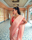 Woman wearing a light pink SónChiraiya Kota silk handloom saree with patterns in gold zari and wide borders featuring peacock and abstract motifs.