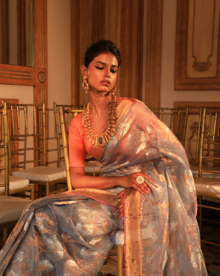 Woman wearing a grey SónChiraiya zari Kota handloom saree with floral motifs in gold and silver zari.   