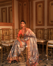 Woman wearing a grey SónChiraiya zari Kota handloom saree with floral motifs in gold and silver zari.   