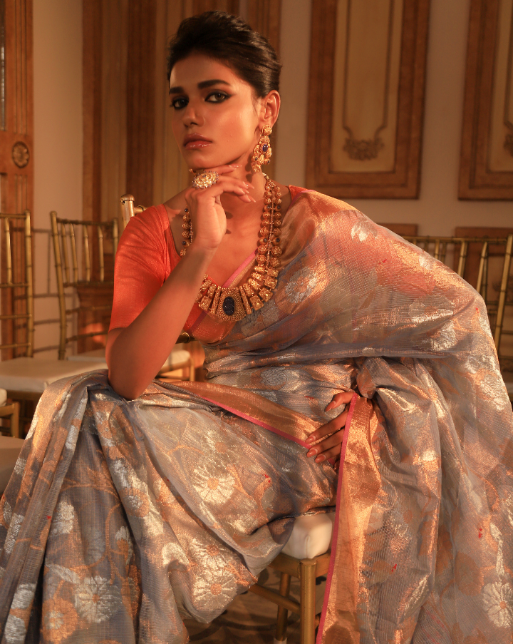 Woman wearing a grey SónChiraiya zari Kota handloom saree with floral motifs in gold and silver zari.   
