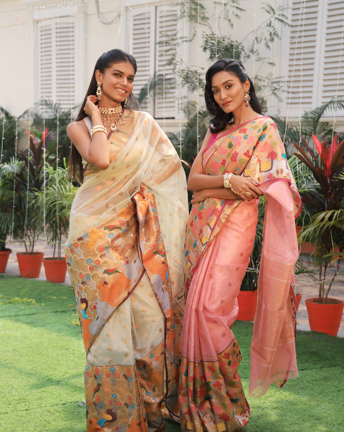 Woman wearing an off-white SónChiraiya zari Kota handloom saree with polka dots in gold zari, a classic Muniya border, and a wide border with various flora and fauna motifs.