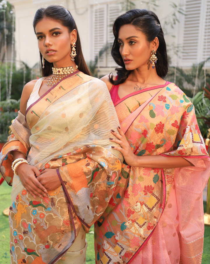 Woman wearing an off-white SónChiraiya zari Kota handloom saree with polka dots in gold zari, a classic Muniya border, and a wide border with various flora and fauna motifs.