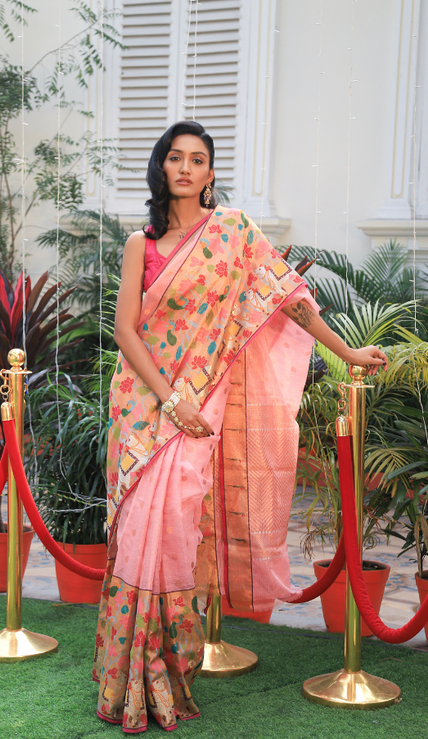 Woman wearing a light pink SónChiraiya zari Kota handloom saree with gold polka dots, Muniya border, and floral and animal motifs in Pichwai art.