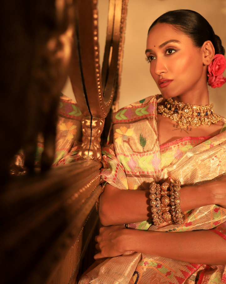 Woman wearing a beige SónChiraiya zari Kota handloom saree with floral, bird and geometric motifs in bright colours.  