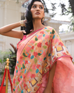 Woman wearing a light pink SónChiraiya zari Kota handloom saree with gold polka dots, Muniya border, and floral and animal motifs in Pichwai art.