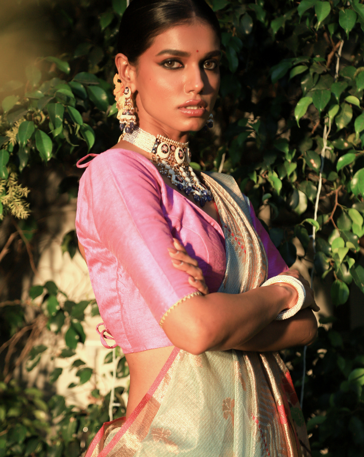 Woman wearing a light blue SónChiraiya Kota silk handloom saree with duck, fish, lotus and other floral motifs with gold and silver zari buttis.