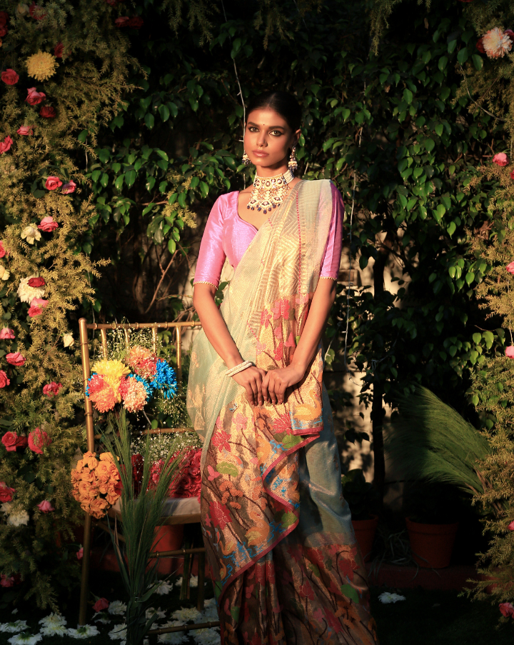 Woman wearing a light blue SónChiraiya Kota silk handloom saree with duck, fish, lotus and other floral motifs with gold and silver zari buttis.