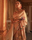Woman wearing a beige SónChiraiya Kota silk handloom saree with geometric motifs in gold zari and large honeycomb patterns in silver zari. 
