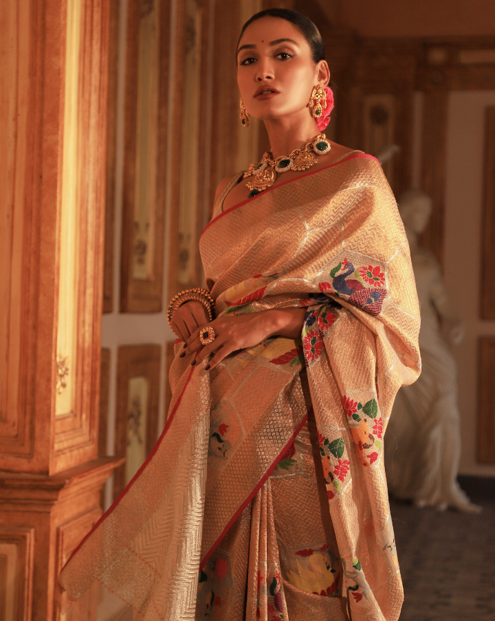 Woman wearing a beige SónChiraiya Kota silk handloom saree with geometric motifs in gold zari and large honeycomb patterns in silver zari. 