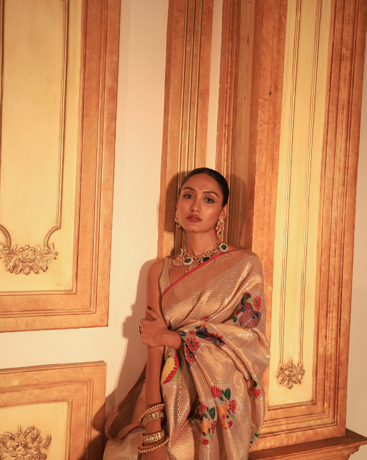 Woman wearing a beige SónChiraiya Kota silk handloom saree with geometric motifs in gold zari and large honeycomb patterns in silver zari. 