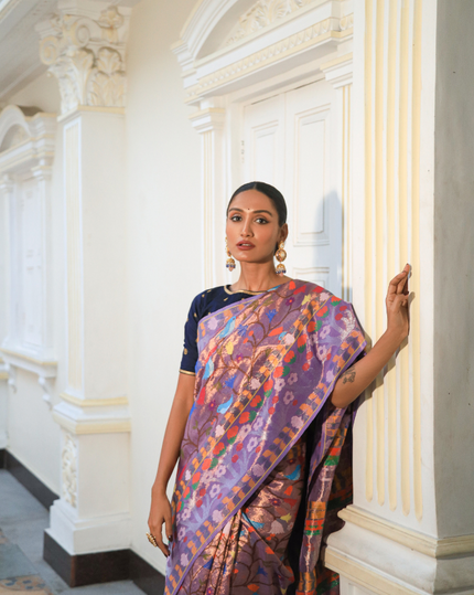 Woman wearing a purple SónChiraiya zari Kota handloom saree with cheerful birds and flowers and wide ornate floral borders.