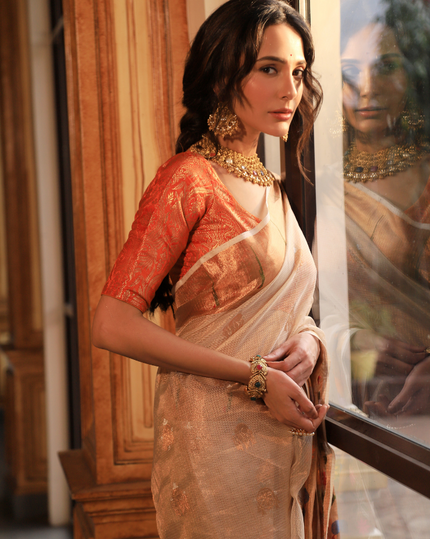 Woman wearing an off-white SónChiraiya zari Kota handloom saree with silver and gold zari buttis, a simple Muniya border, and a wide ornate floral border.  