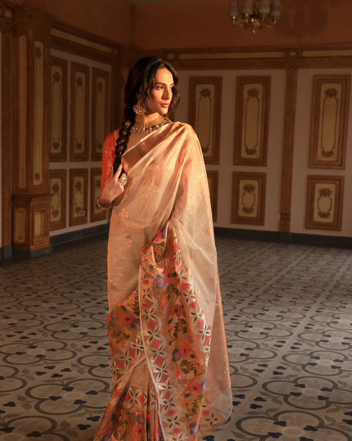 Woman wearing an off-white SónChiraiya zari Kota handloom saree with silver and gold zari buttis, a simple Muniya border, and a wide ornate floral border.  
