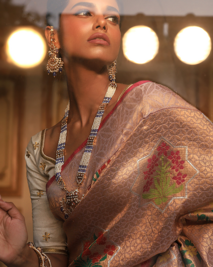 Woman wearing a blush pink SónChiraiya Kota silk handloom saree with geometric floral motifs in gold zari, and bright-hued bunches of flowers.