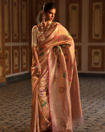Woman wearing a blush pink SónChiraiya Kota silk handloom saree with geometric floral motifs in gold zari, and bright-hued bunches of flowers.