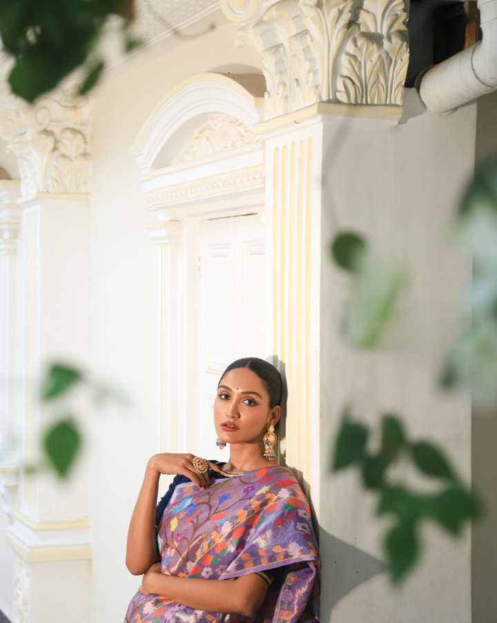 Woman wearing a purple SónChiraiya zari Kota handloom saree with cheerful birds and flowers and wide ornate floral borders.