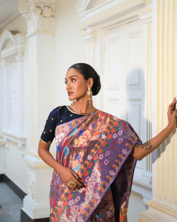 Woman wearing a purple SónChiraiya zari Kota handloom saree with cheerful birds and flowers and wide ornate floral borders.