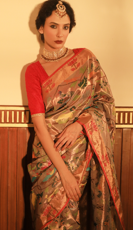 Woman wearing a beige SónChiraiya zari Kota handloom saree with floral vines intertwined with Mughal jaal, animal and bird motifs and bright lotuses.  