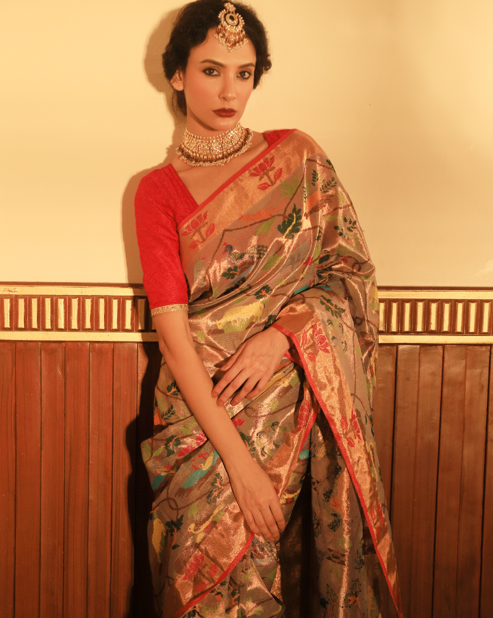 Woman wearing a beige SónChiraiya zari Kota handloom saree with floral vines intertwined with Mughal jaal, animal and bird motifs and bright lotuses.  