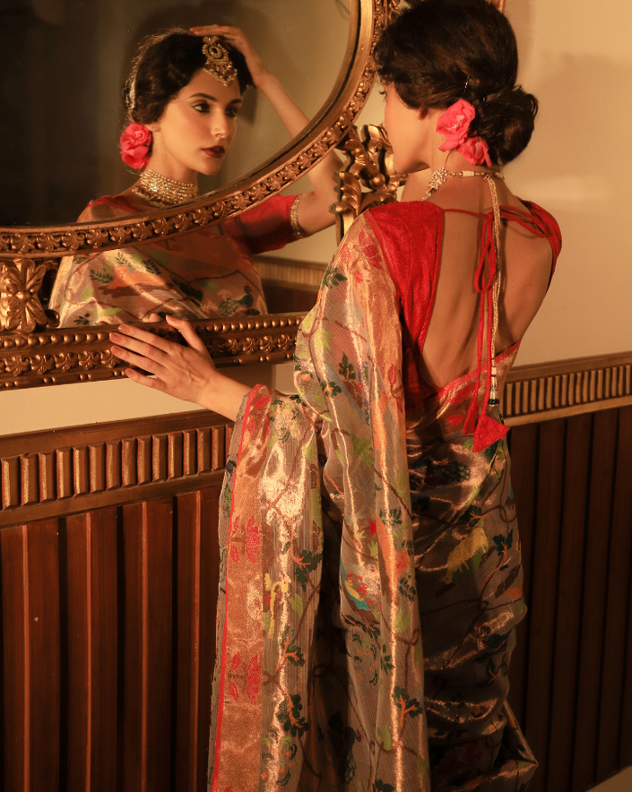 Woman wearing a beige SónChiraiya zari Kota handloom saree with floral vines intertwined with Mughal jaal, animal and bird motifs and bright lotuses.  