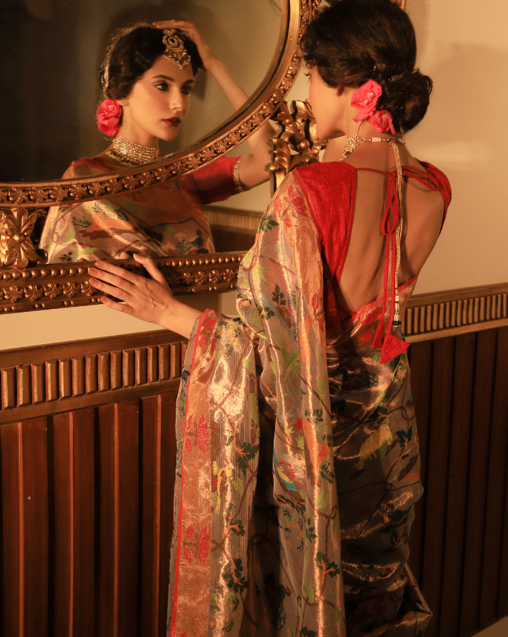 Woman wearing a beige SónChiraiya zari Kota handloom saree with floral vines intertwined with Mughal jaal, animal and bird motifs and bright lotuses.  