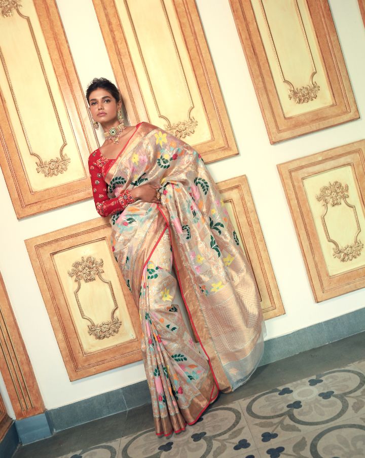 Woman wearing an off-white SónChiraiya zari Kota handloom saree with many-hued florals and gold and silver zari geometric motifs.  