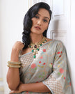Woman wearing a grey SónChiraiya zari Kota handloom saree with colourful flowers, gold and silver zari accents and ornate borders.
