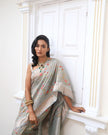 Woman wearing a grey SónChiraiya zari Kota handloom saree with colourful flowers, gold and silver zari accents and ornate borders.
