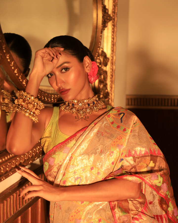 Woman wearing a beige SónChiraiya zari Kota handloom saree with floral, bird and geometric motifs in bright colours.  