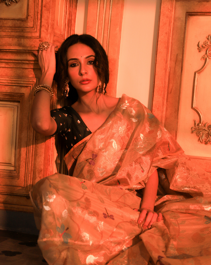 Woman wearing a beige SónChiraiya zari Kota handloom saree with floral motifs, bright dragonflies and Muniya border.