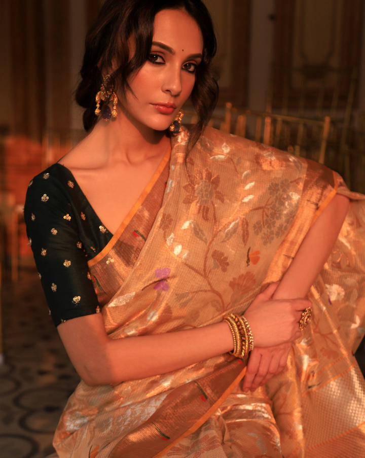 Woman wearing a beige SónChiraiya zari Kota handloom saree with floral motifs, bright dragonflies and Muniya border.