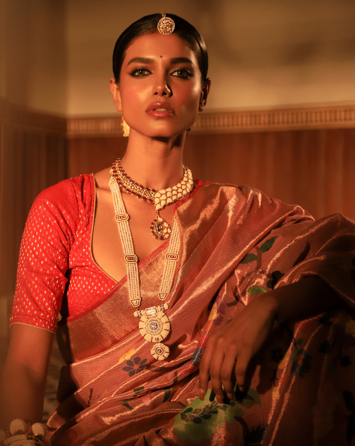 Woman wearing a peach SónChiraiya zari Kota handloom saree with vibrant floral blooms.  